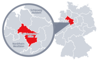Diese Grafik zeigt eine Karte von Deutschland mit einer detaillierten Ansicht der Region Niedersachsen-Mitte. Niedersachsen-Mitte ist in Rot hervorgehoben und liegt im Nordwesten von Deutschland. Ein Lupensymbol vergrößert diesen Bereich, um die Lage genauer darzustellen.